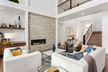 Beautiful living room interior in new luxury home with large stone fireplace surround, hardwood...
