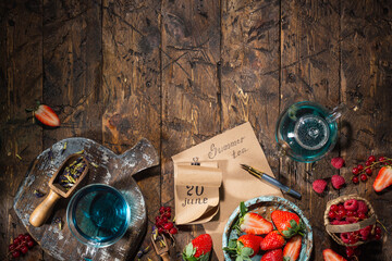 Berry still life. Berries, tea, pen, calendar, notebook on an old brown wooden table, top view