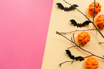 Halloween decorations with pumpkin and bats and branches on pastel beige pink background. Halloween concept. Flat lay, top view, copy space