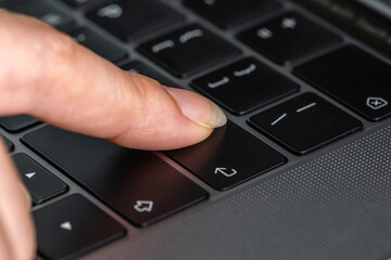 close-up female hand pressing enter button on laptop keyboard