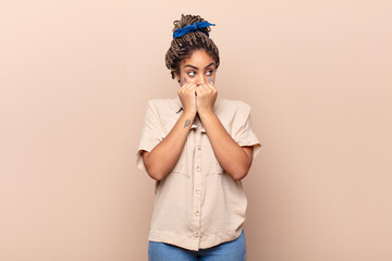 young afro woman looking worried, anxious, stressed and afraid, biting fingernails and looking to...