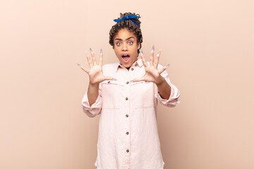 young afro woman feeling terrified, backing off and screaming in horror and panic, reacting to a...