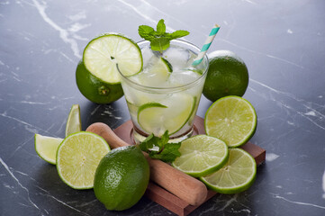 Caipirinha cocktail in glass on marble table, lemon slices and mint