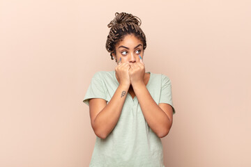 young afro woman looking worried, anxious, stressed and afraid, biting fingernails and looking to...