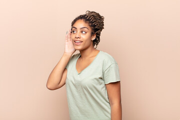 young afro woman smiling, looking curiously to the side, trying to listen to gossip or overhearing...