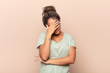 young afro woman looking stressed, ashamed or upset, with a headache, covering face with hand