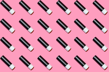 Obraz premium Background of small tubes of lipstick on a pink background. Cosmetics for lips. Seamless.