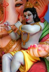 Close-up view of Indian Hindu God Krishna on the lap of Ganesha idol