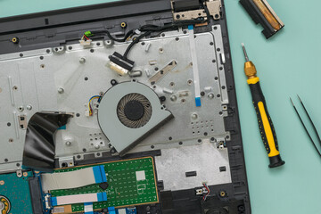 Fototapeta premium CPU cooling fan and disassembled laptop on a blue background.
