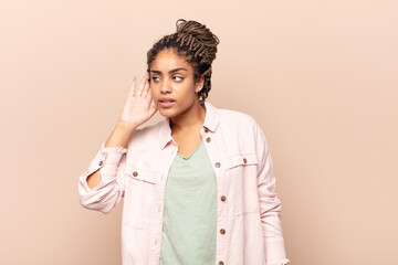 young afro woman looking serious and curious, listening, trying to hear a secret conversation or...