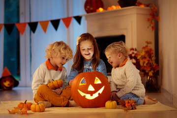 Fototapeta premium Kids carving pumpkin on Halloween. Trick or treat.