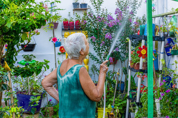Mulher idosa cuida de molha jardim florido
