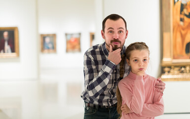 friendly father and daughter regarding paintings in halls of museum