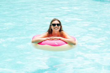 Beautiful woman with inflatable donut in swimming pool