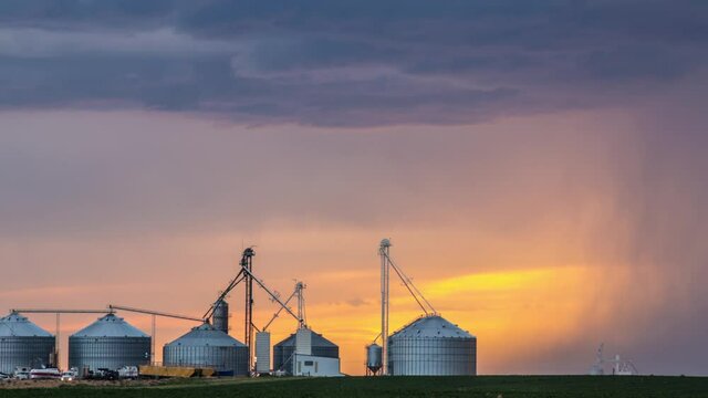 Sun setting in dramatic sky over grain silos