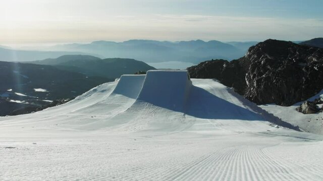 Freshly groomed kicker at snow park ready to be jumped during sunset, sideways