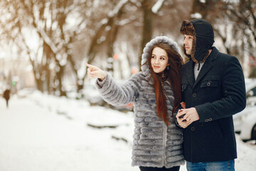 Cute couple walking in a winter city. Elegant woman in a gray fur coat