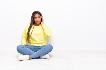young afro woman looking serious and curious, listening, trying to hear a secret conversation or...