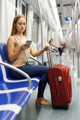 Fototapeta na wymiar Girl passenger using mobile phone in subway to entertain during transportation