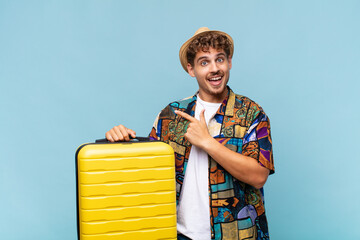 young man looking excited and surprised pointing to the side and upwards to copy space. holidays...