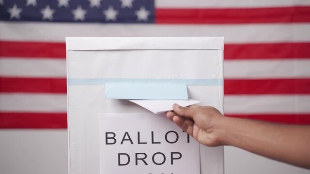 Maski, India 14 September, 2020 : Concept of Absentee Ballot Mail in voting at US election - hands dropping mail inside the ballot box with us flag as background.
