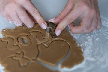 A girl cuts out Christmas cookies from the dough with pastry forms.