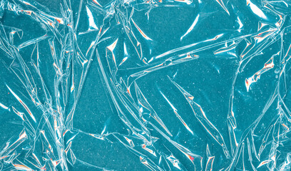 Shiny abstract background. Grain texture. Wrinkled transparent film on teal blue sparkling surface.