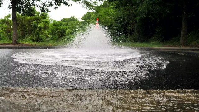 In front of fire hydrant while water is spraying out.