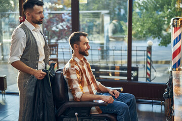 Qualified barber and his client looking in the mirror