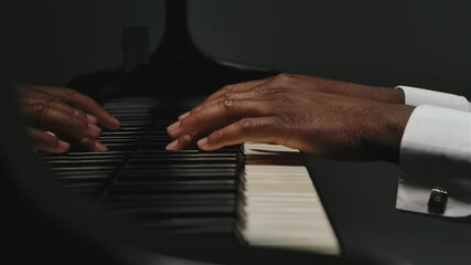 Footage of male hands playing the grand piano. An African American man touches his fingers on the black and white keys. The pianist plays the beautiful grand piano in slow motion. Close up. - Powered by Adobe