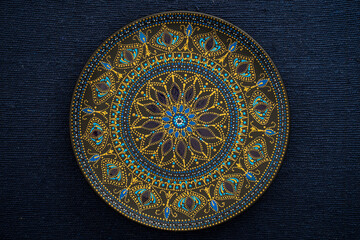 Decorative ceramic plate with black, blue and golden colors, painted plate on background of blue...