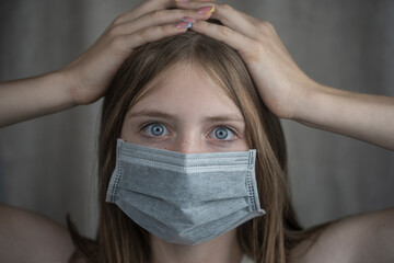 Studio portrait of young girl wearing a face mask, close up, on gray background. Copy space