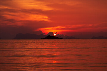 Beautiful red sunset over sea water. Sun, colorful sky and clouds over dark sea