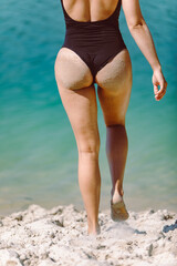 woman wet ass in sand black swimsuit