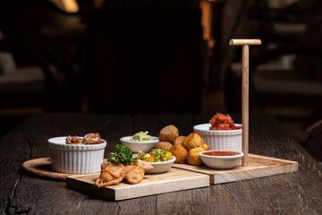 Spanish food ingredients on dark old wooden background, appetizers knowns as tapas with seafood, fish, meet, red sauces, greens, vegetables. Healthy food. Vegan, vegetarian on the white plate.