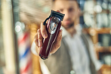 Professional electric hair clipper being held by a barber