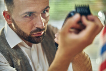 Professional hair-styling specialist cleaning his hair clipper