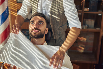 Bearded client of a barbershop before hair-grooming procedures