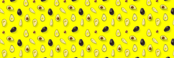 Avocado banner. Background made from isolated Avocado pieces on yellow background. Flat lay of fresh ripe avocados and avacado pieces.