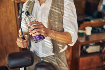 Professional hair-stylist holding a spray bottle at barbershop