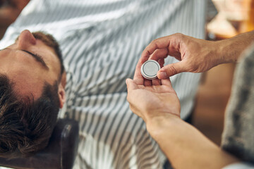 Fototapeta premium Hair-stylist holding a tiny tin can with hair wax