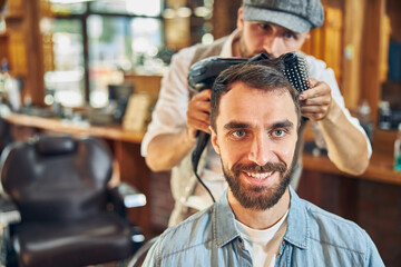 Obraz premium Young brunette man having an appointment at barbershop