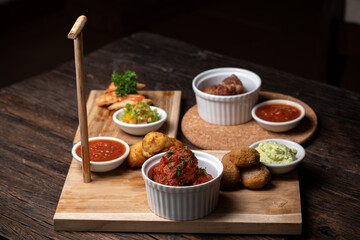 Spanish food ingredients on dark old wooden background, appetizers knowns as tapas with seafood, fish, meet, red sauces, greens, vegetables. Healthy food. Vegan, vegetarian on the white plate.