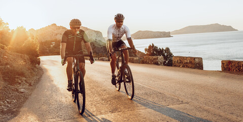 Two professional male cyclists riding their racing bicycles in the morning together
