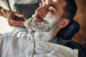 Relaxed man covered in shaving cream at hair salon