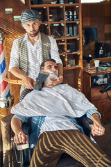 Determined hair-stylist shaving his client with an axe