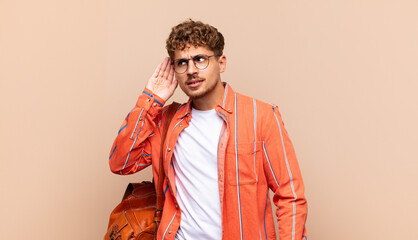 young man looking serious and curious, listening, trying to hear a secret conversation or gossip,...