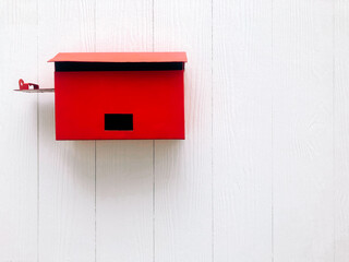 Red mailbox on white wooden wall