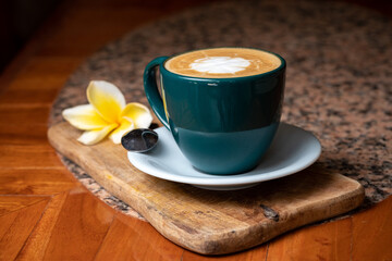 Coffee cup on stone kitchen table. Cappuccino, hot latte or coffee with milk cup on the white plate the wood board. Flower Frangipani. Yellow, white, brown. Healthy, vegan, vegetarian, almond milk
