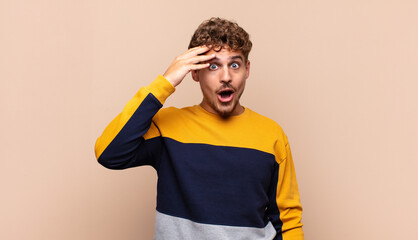 young man looking happy, astonished and surprised, smiling and realizing amazing and incredible...